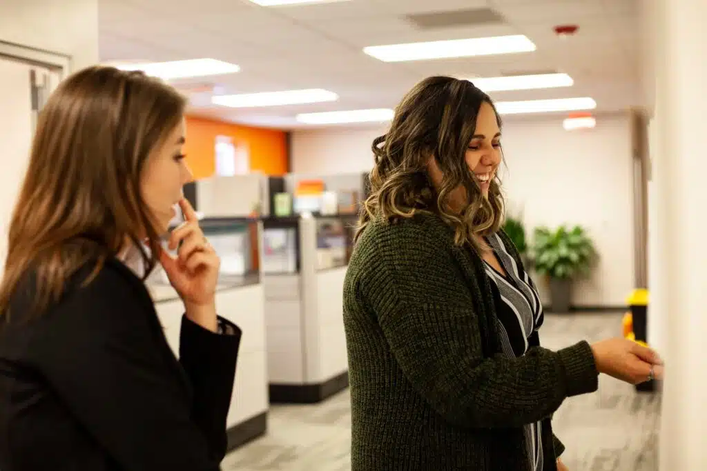 Two Nonprofit Workers writing on a whiteboard in an office setting