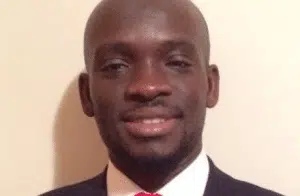 Samba Mboup, nonprofit professional, smiling in a full suit with a red tie