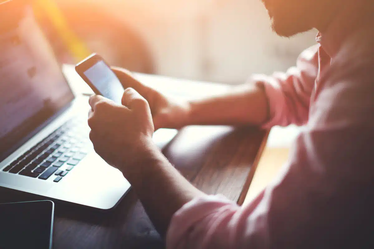 A man uses a mobile phone and laptop to experience the donor journey