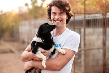 Teenage Boy with a volunteer shirt holding a black and white dog