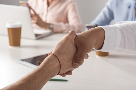 Two people shaking hands in an office over a business meeting