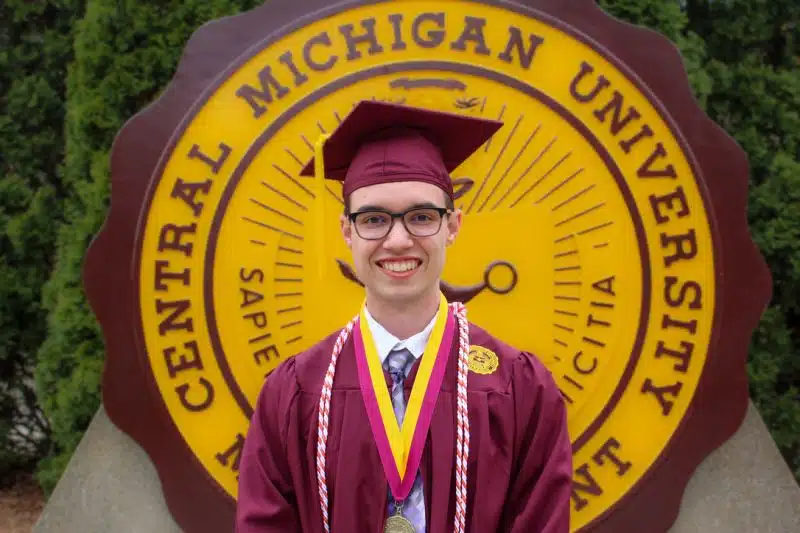 Campus Partner, Central Michigan University graduate dressed in maroon regalia with orange certified nonprofit professional cords around their neck