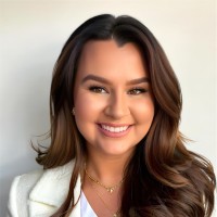 Julianna Jones smiling with dark brown hair and white professional blazer in front of a white background