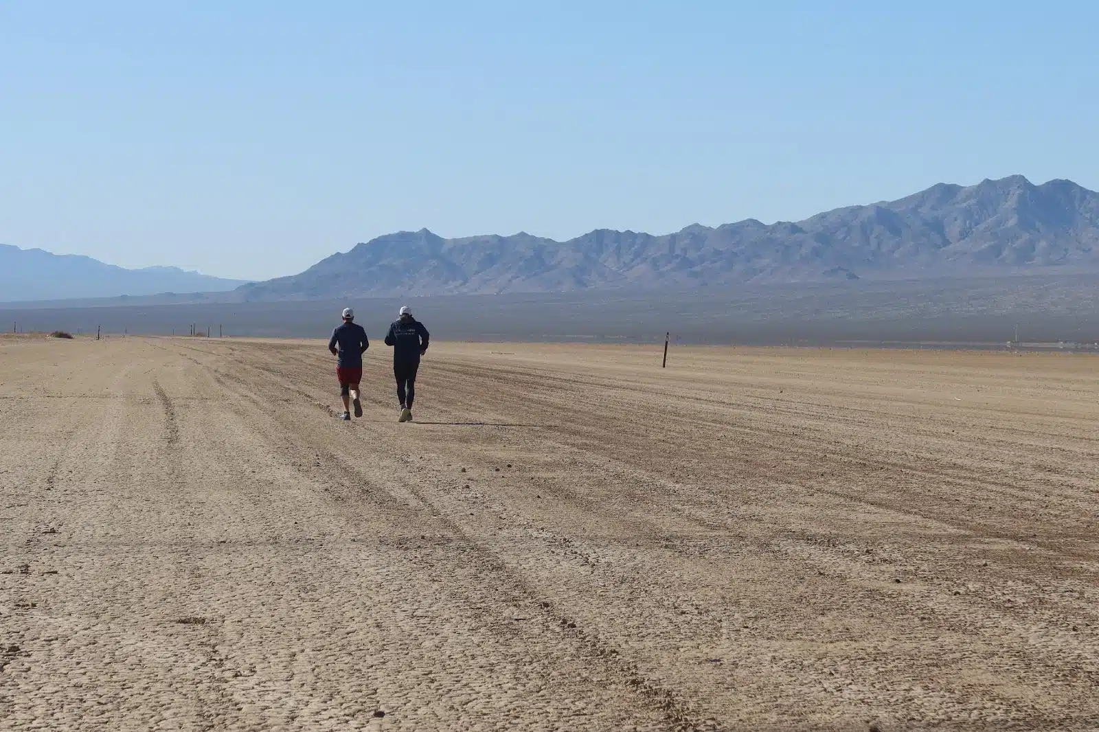 Two individuals running away from us during a charity run in las vegas. You can see the mountains in the background