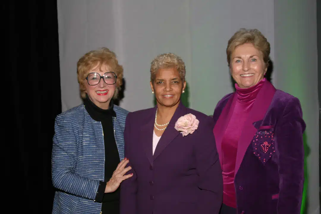 A group of three professionally dressed women in short hair