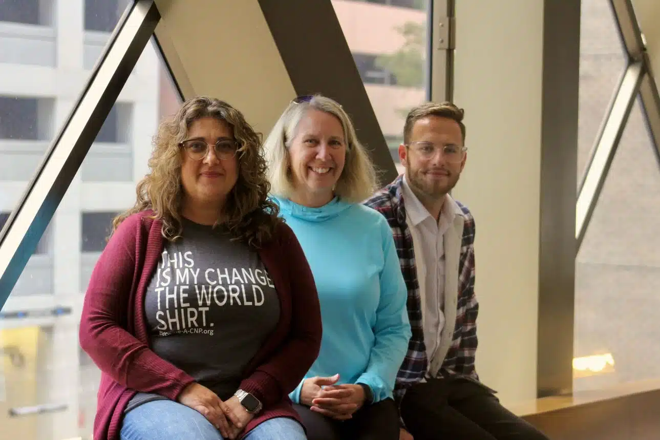 Three nonprofit leadership alliance students smiling and sitting at a conference