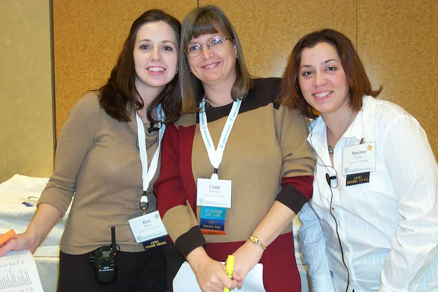 Three nonprofit professional women smiling with lanyards on