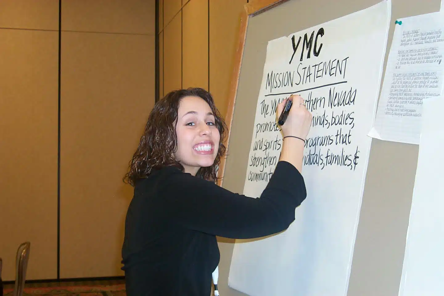 Biracial woman smiling and writing on a large board