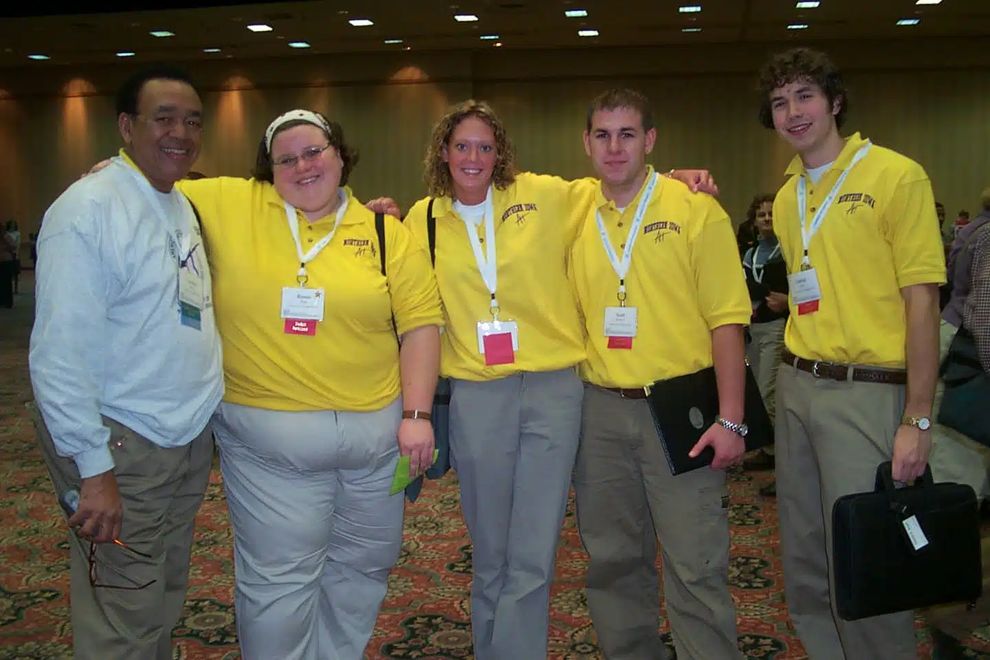 Group of 4 nonprofit professionals smiling in matching yellow polos