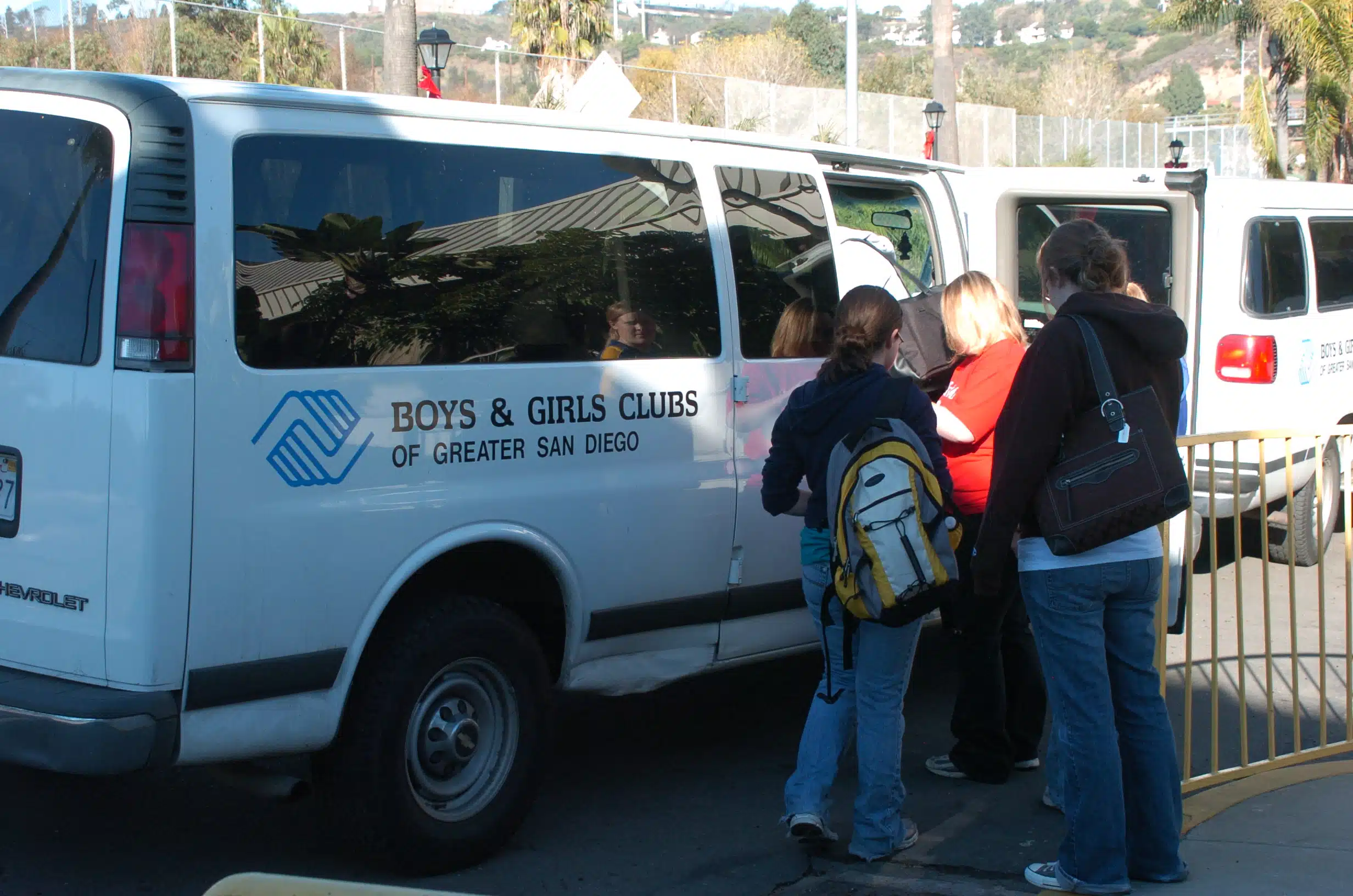 Individuals entering a white Boys and Girls Club branded van