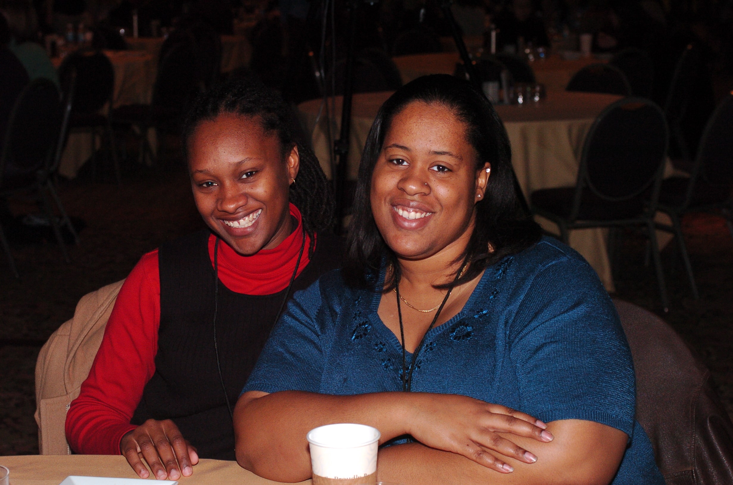 Two african american women smiling brightly while sitting at a table