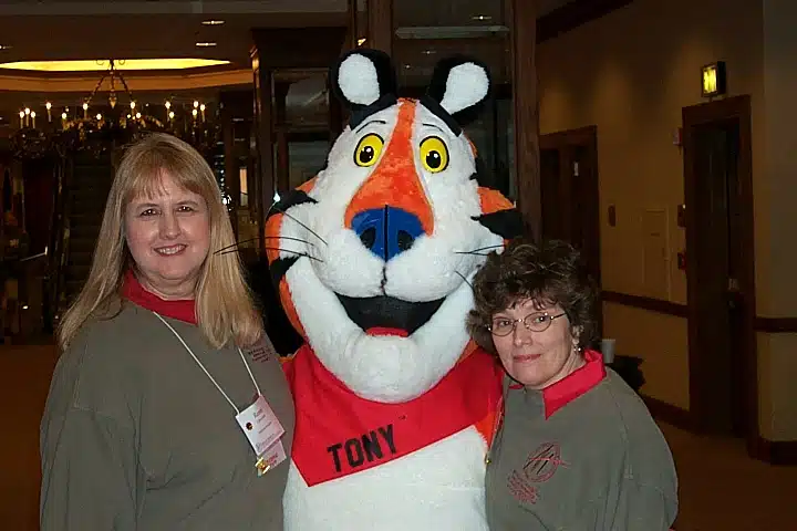 Two women smiling with Tony the Tiger at the nonprofit leadership alliance conference