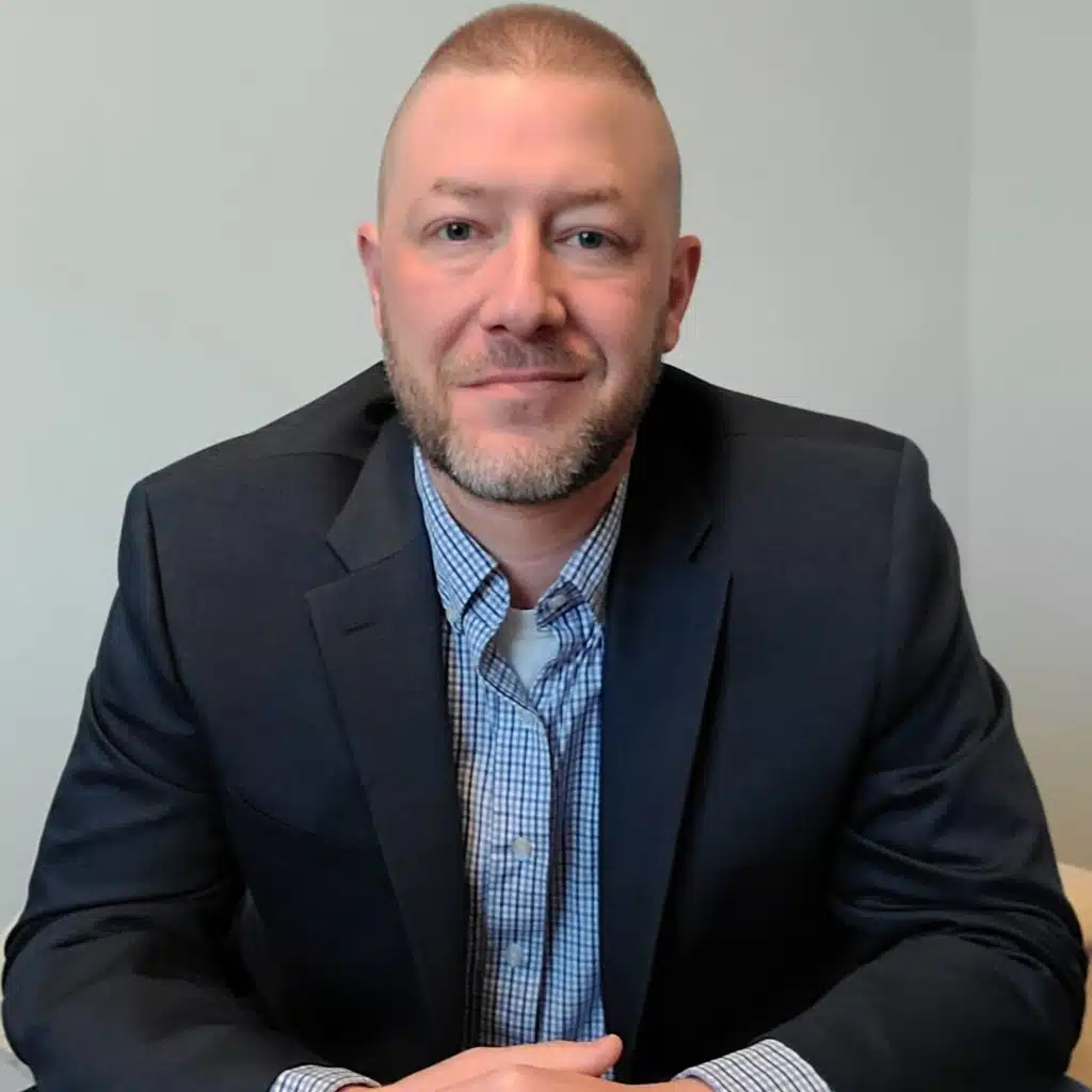 Certified Nonprofit Professional, Scott Myers Smiling in a grey suit jacket and blue professional button down