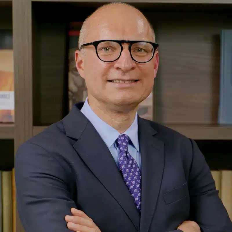 Jose Luis Castro smiling in a grey suit and purple tie