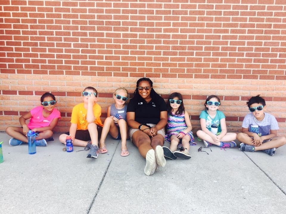 Certified Nonprofit Professional, Maigan T. Bridgette sitting on the ground with a group of YMCA Kansas City students