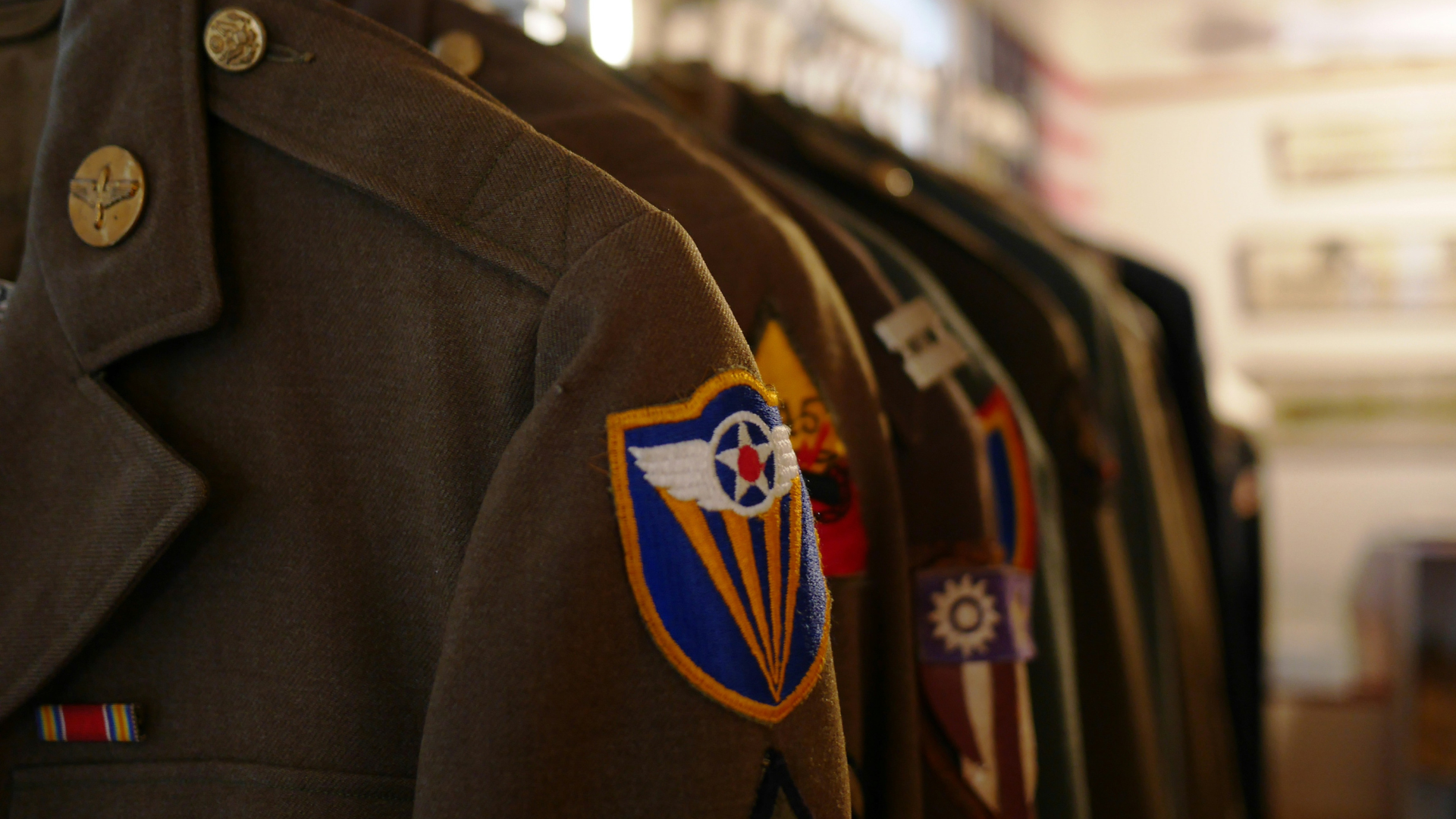 Military uniforms hung up in a row