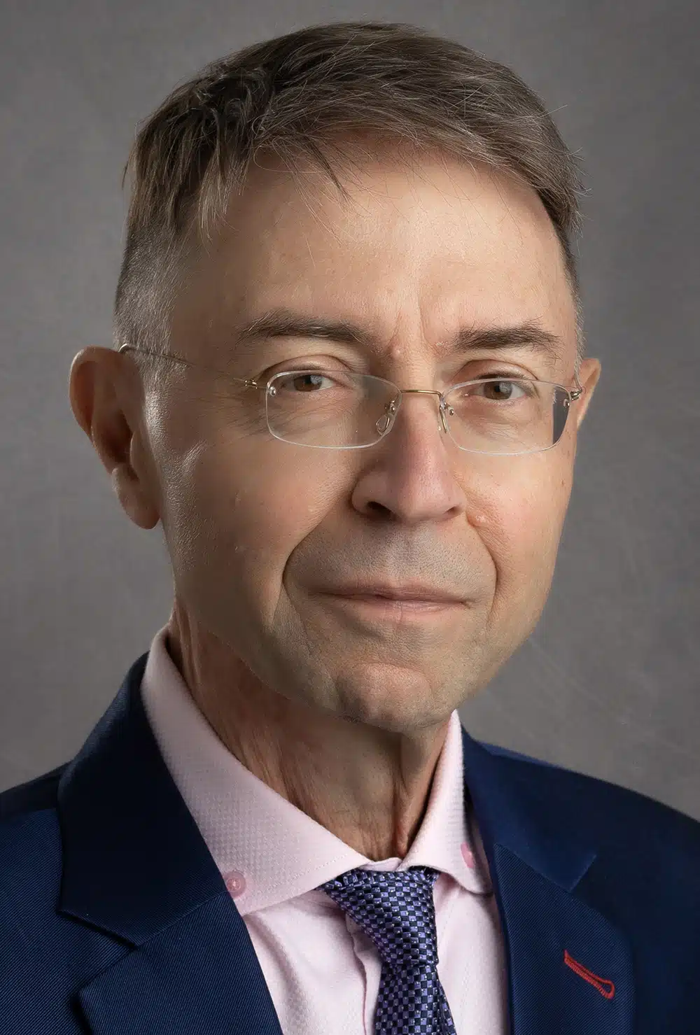 Professionally dressed man in a pink shirt and navy blazer