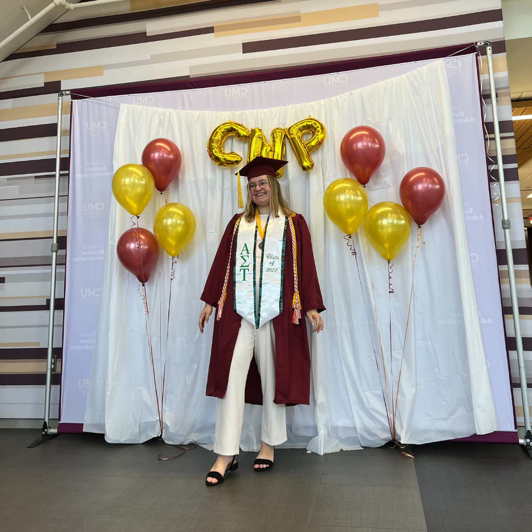 Lizzie Dilg, Certified Nonprofit Professional, smiling in her cap and gown from Central Michigan University with big balloons behind her spelling out "CNP"