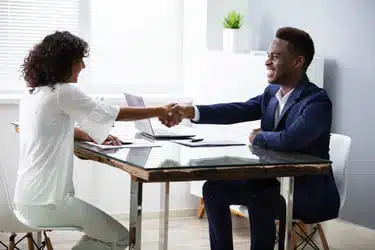 Two people shake hands during an interview