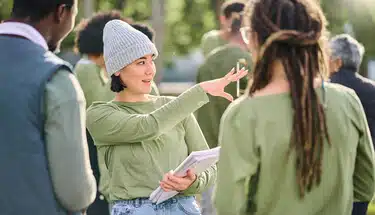 A volunteer leader directs two other volunteers while holding a stack of papers.