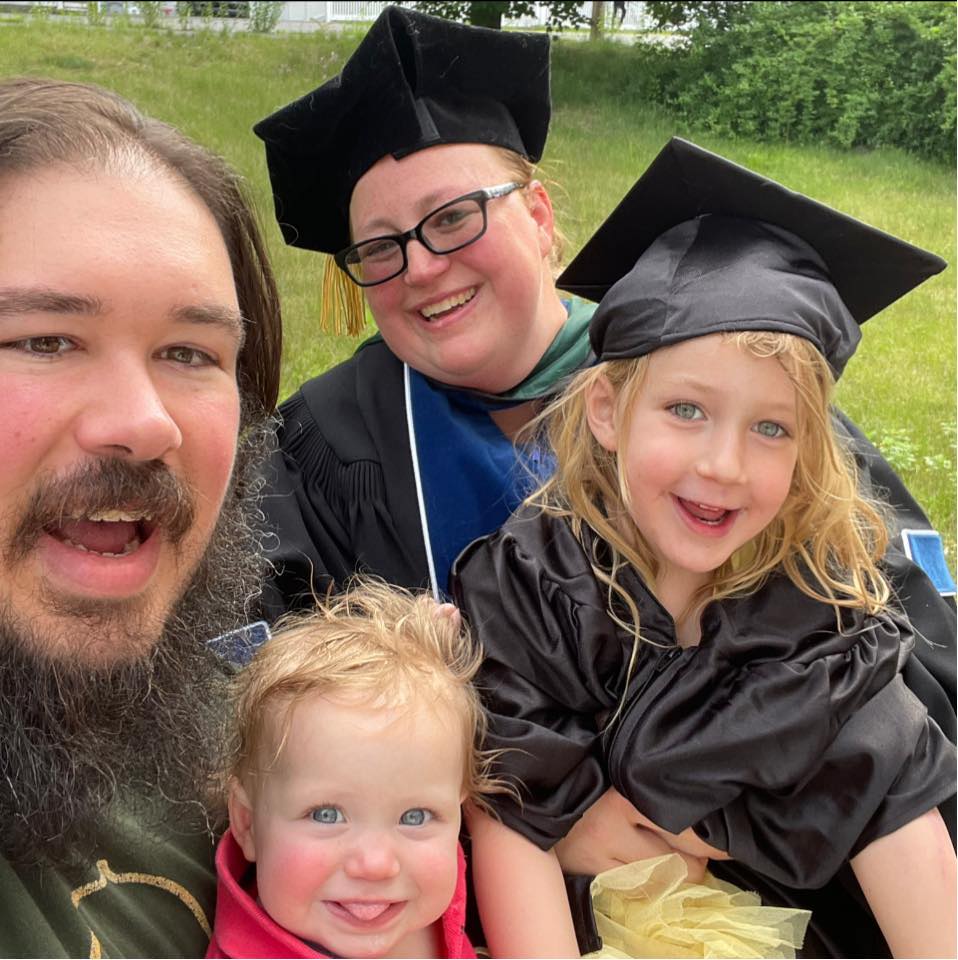 Dr Sara smiling with her husband and two children after earning her degree