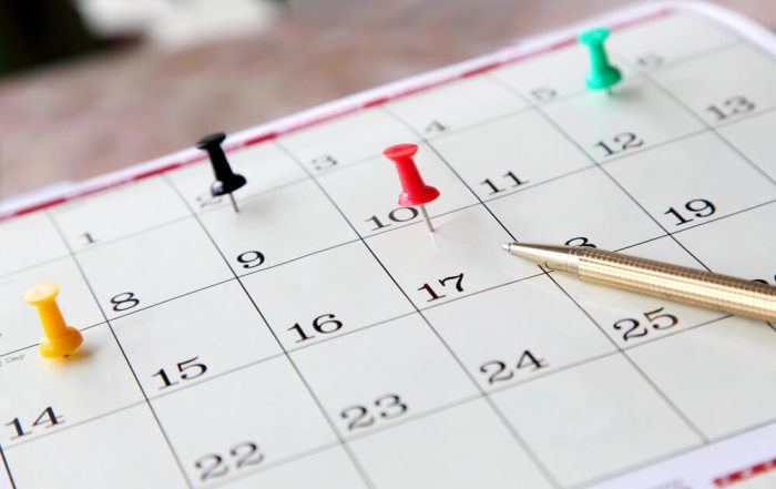 A close-up of a calendar page with push pins marking specific fundraising dates