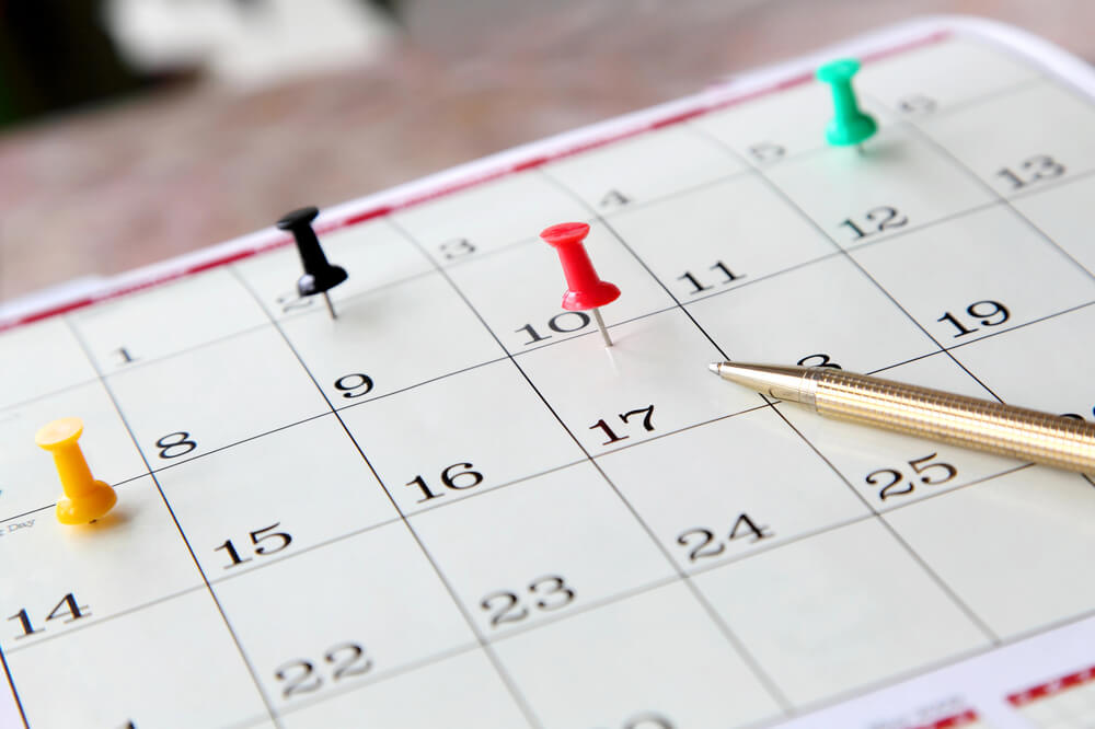 A close-up of a calendar page with push pins marking specific fundraising dates