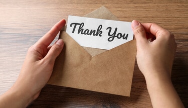 Opening a brown envelope that includes a thank you note